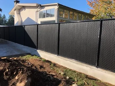 Black chain-link fence fitted with black privacy slats