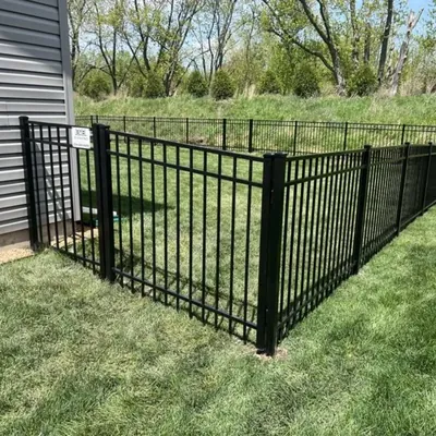Black aluminum fence and walk gate on a green lawn