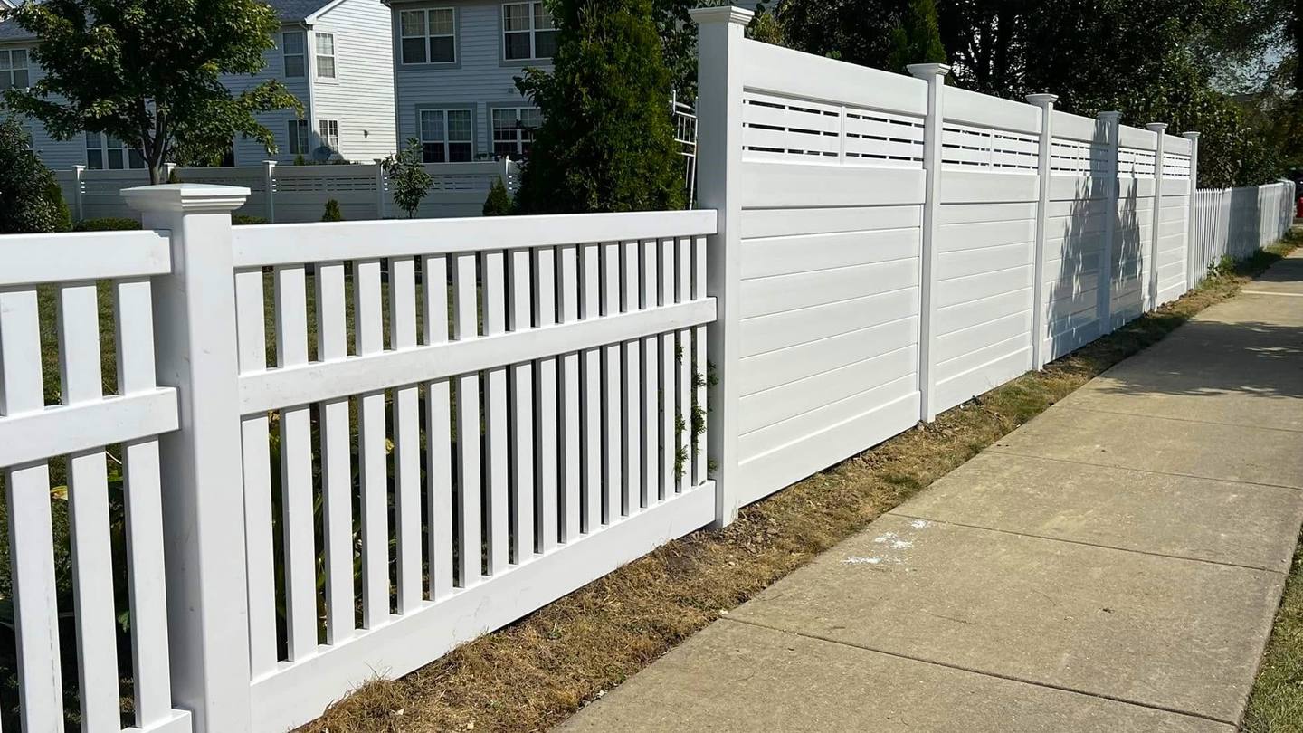 New white vinyl fence along a sidewalk in the Chicago suburbs, with privacy panels and a slatted top next to an open picket section, installed by Diamond Fence Corp.