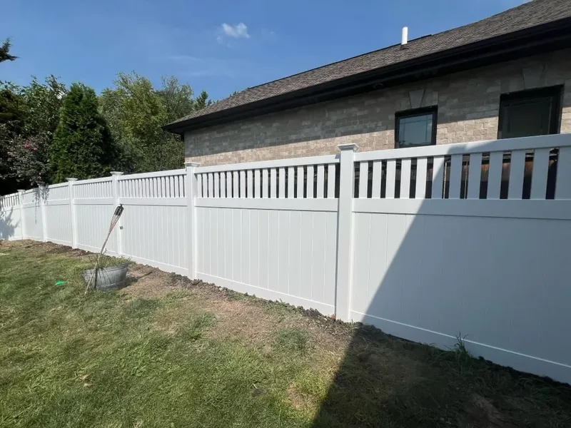 White vinyl privacy fence with a picket top beside a brick home in the Chicago suburbs